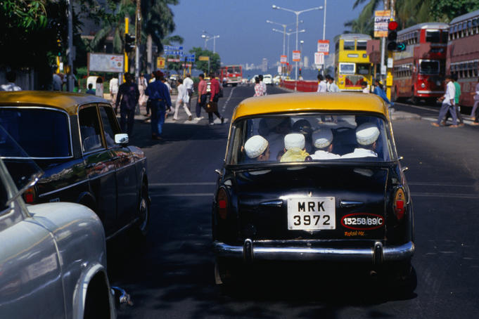 Passengers in a taxi stop at an intersection in Mumbai.