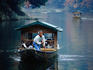 A boatman poling a pleasure boat along a river in Kyoto.