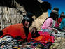 Souvenir sellers in big hats, sitting with their wares outside straw houses on Tribuna Island - Lake Titicaca, Puno