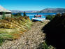 One boat on the lake and another on the shore beside a harvest on Balsero Island - Lake Titicaca, Puno