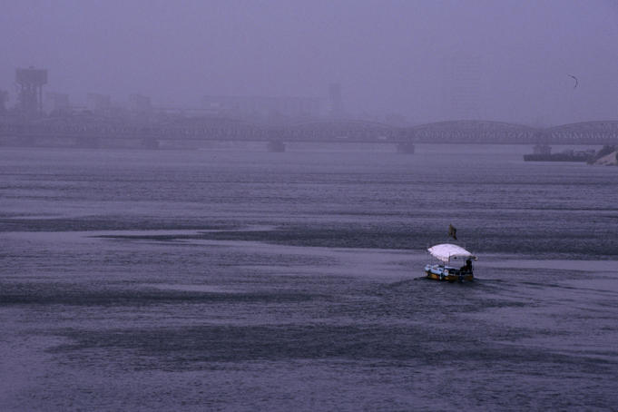 A boat makes its way up the River Nile, while central Cairo is covered with a mixture of sand and smog