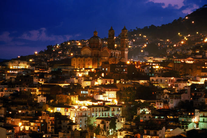 Iglesia Santa Prisca and hillside houses lit up at dusk, Taxco