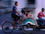 Becak and scooter on city street.