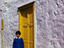 Boy in front of his traditional white-washed house, setting out for school.