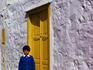 Boy in front of his traditional white-washed house, setting out for school.