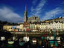 St Colman's Cathedral with shopfronts and harbour in foreground.