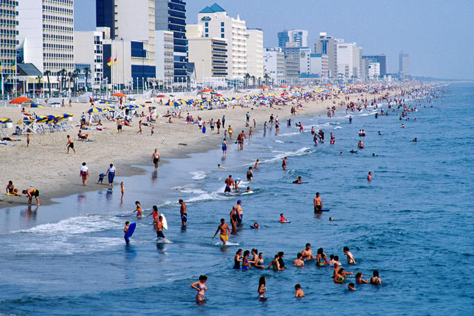 Crowds swimming in beach.