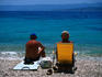 A middle-aged couple soaking up the sun on a pebble beach.