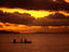 Sunset over the sea with an outrigger in silhouette.