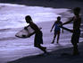 Young surfers on black-sand beach.