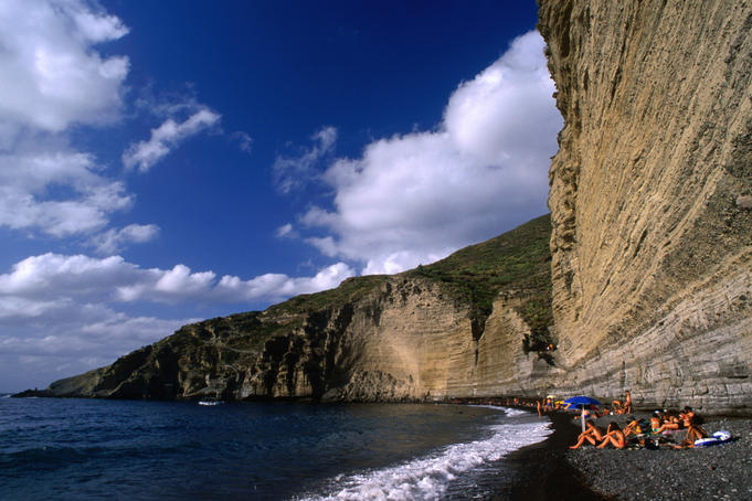 Narrow and dwarfed by the cliff behind stretches the well attended pebble beach of Pollara, Salina island.