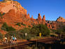 Cyclists, passing below the Chapel of the Holy Cross, explore red-rock country around Sedona.