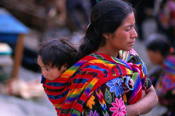 Mayan woman carrying her baby in a sling on her back.