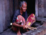 An elderly woman plays the xylophone on the verandah of her stilt house in Kampung Penambawan.