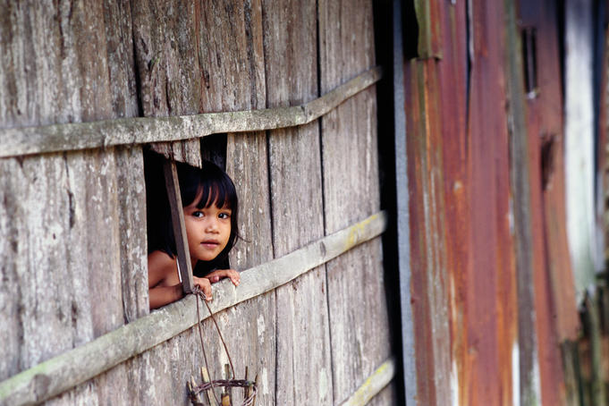 A young girl peers through a broken fence at Menyang Sedi Longhouse near Lake Batang Ai.