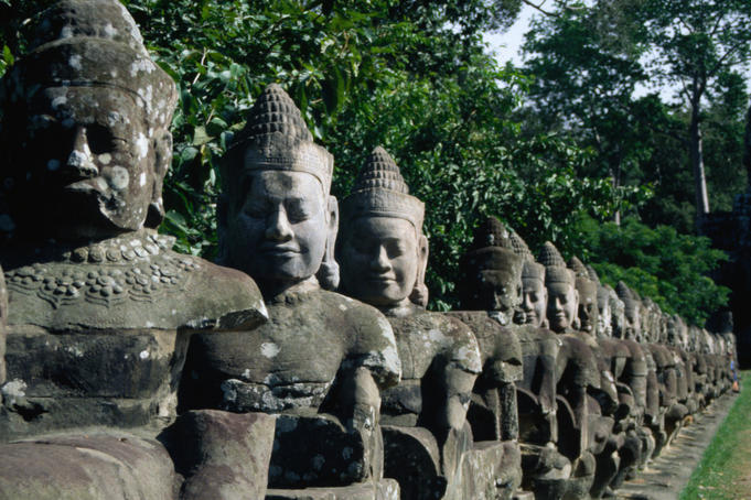 Stone statues of the fifty-four mythical gods who hold a naga at the South Gate to Angkor Thom, many of which have been decapitated by thieves and vandals.