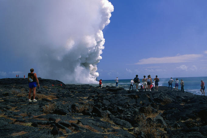 Tourists walk out to the smoking lava flow in the Hawaii Volcanos National Park.
