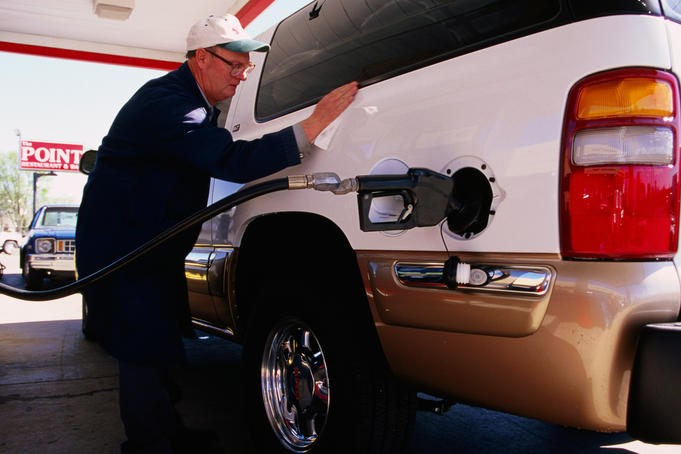 Service station attendant filling up vehicle with petrol.
