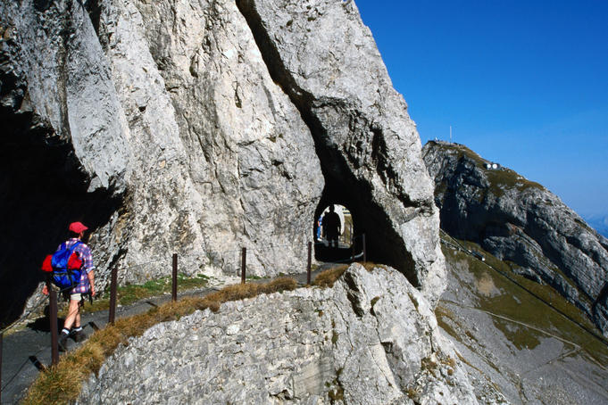 Hikers on Hohenweg with the tunnel leading from the top down to Lake Lucerne.