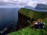 Overhead of hiker on cliff at Kallur, overlooking Kunoyarnakkur (elevation 819m) on Kunoy island and Ennilberg (elevation 754m) on Vidoy island.