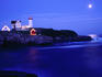 Nubble lighthouse alight underneath moon-lit sky.