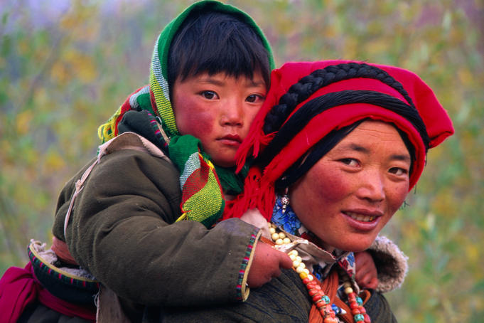 Tibetan woman carrying a young child on her back.