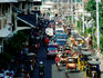 Traffic & pedestrians on street outside city market.