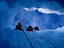 Three explorers looking through hole in ice.