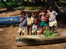 Group of local children on the beach beside a wooden boat.