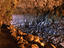 Man standing amongst rocks (left) and light streaming across rocks near entrance to Skull Cave.