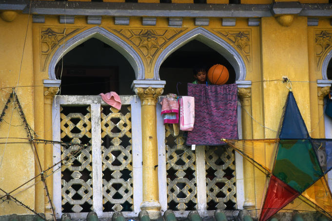 Child plays with basketball on house balcony.