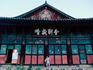 A monk sweeps outside the front entrance to a Buddhist temple.